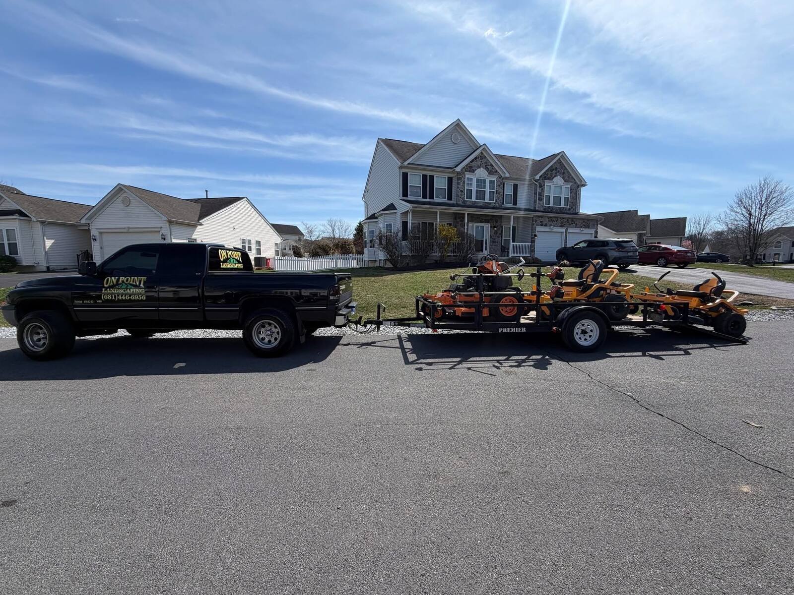 On Point Landscaping truck and trailer loaded with commercial mowers