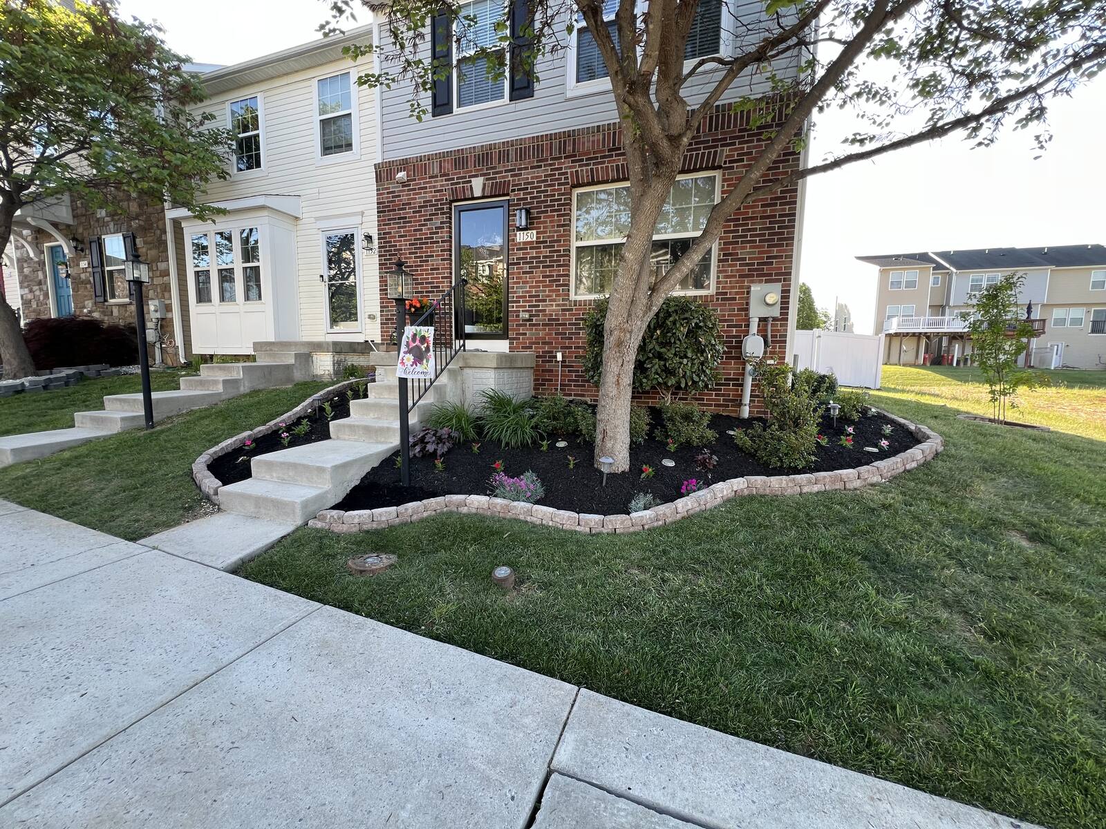 Stone-edged flower bed with fresh black mulch and new plantings