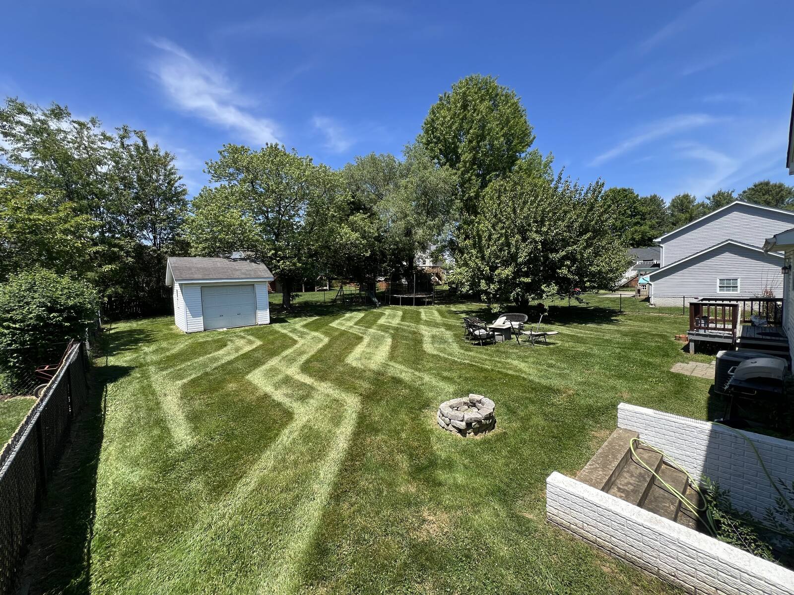 Freshly mowed backyard with crosshatch stripes around a stone fire pit