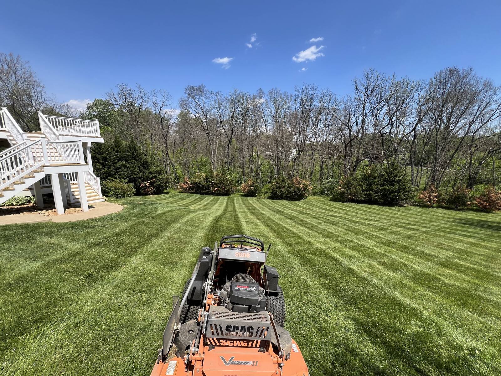 Zero-turn mower cutting clean stripes across a large backyard
